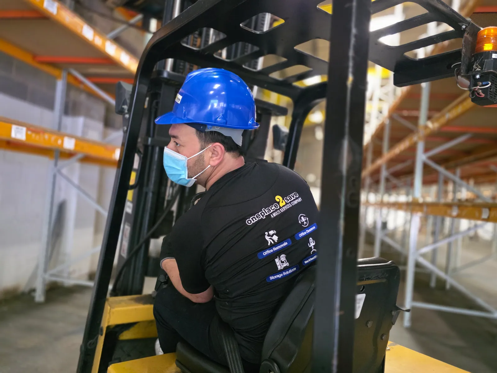 Oneplace2save team member operating a forklift in storage