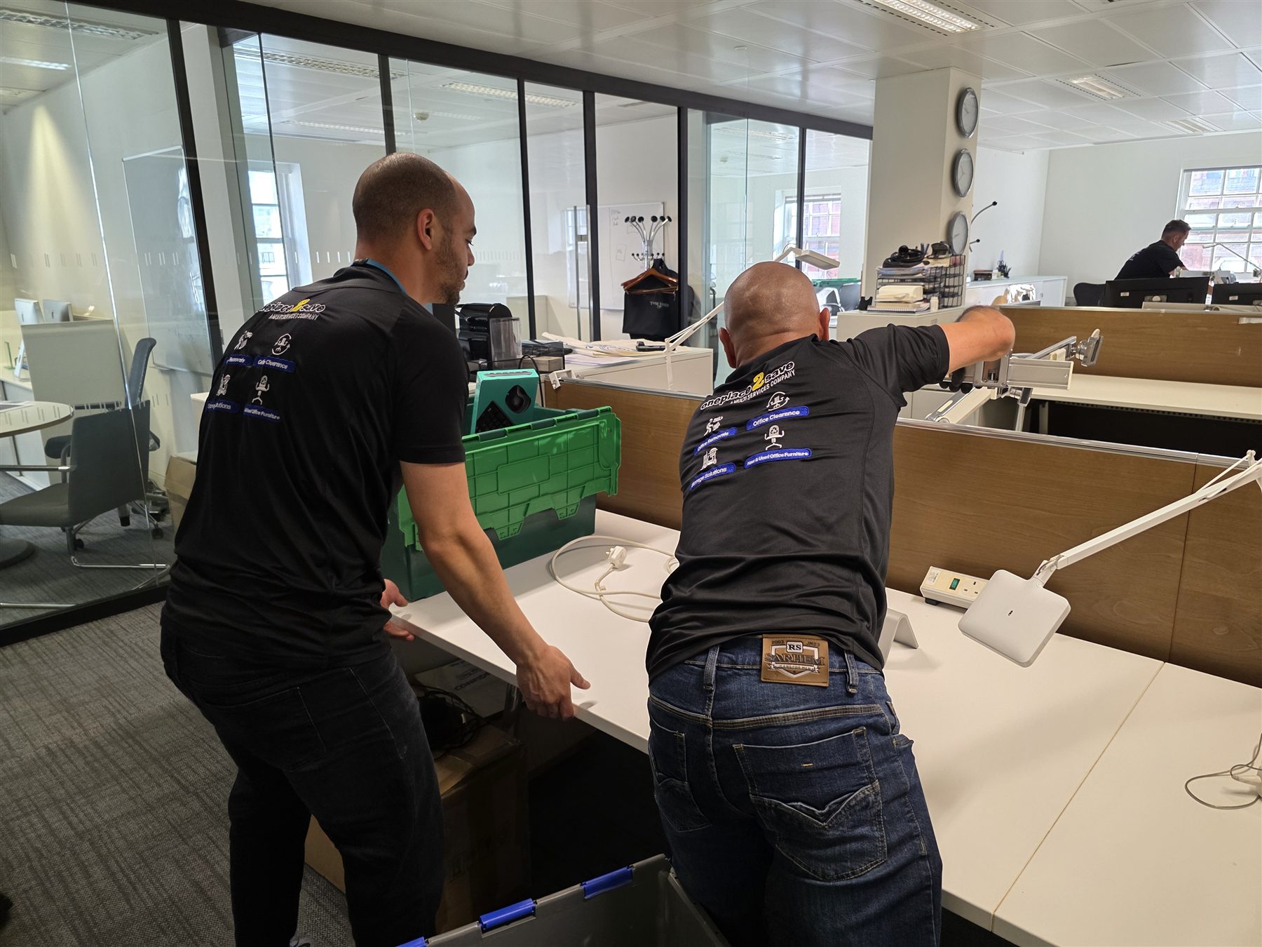 Two Oneplace2save team members handling a desktop during an office removal.