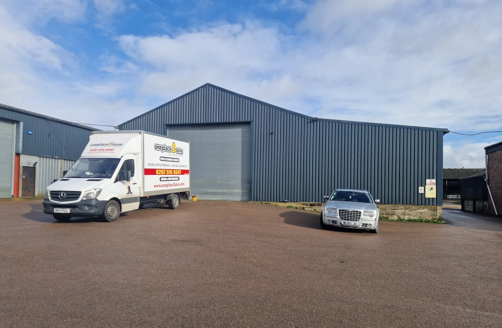 A branded Oneplace2save removal van parked outside warehouse units.