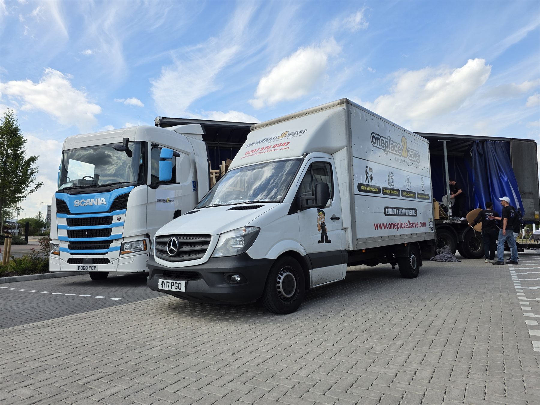 A Oneplace2save Luton van and a larger removal vehicle at a loading area.