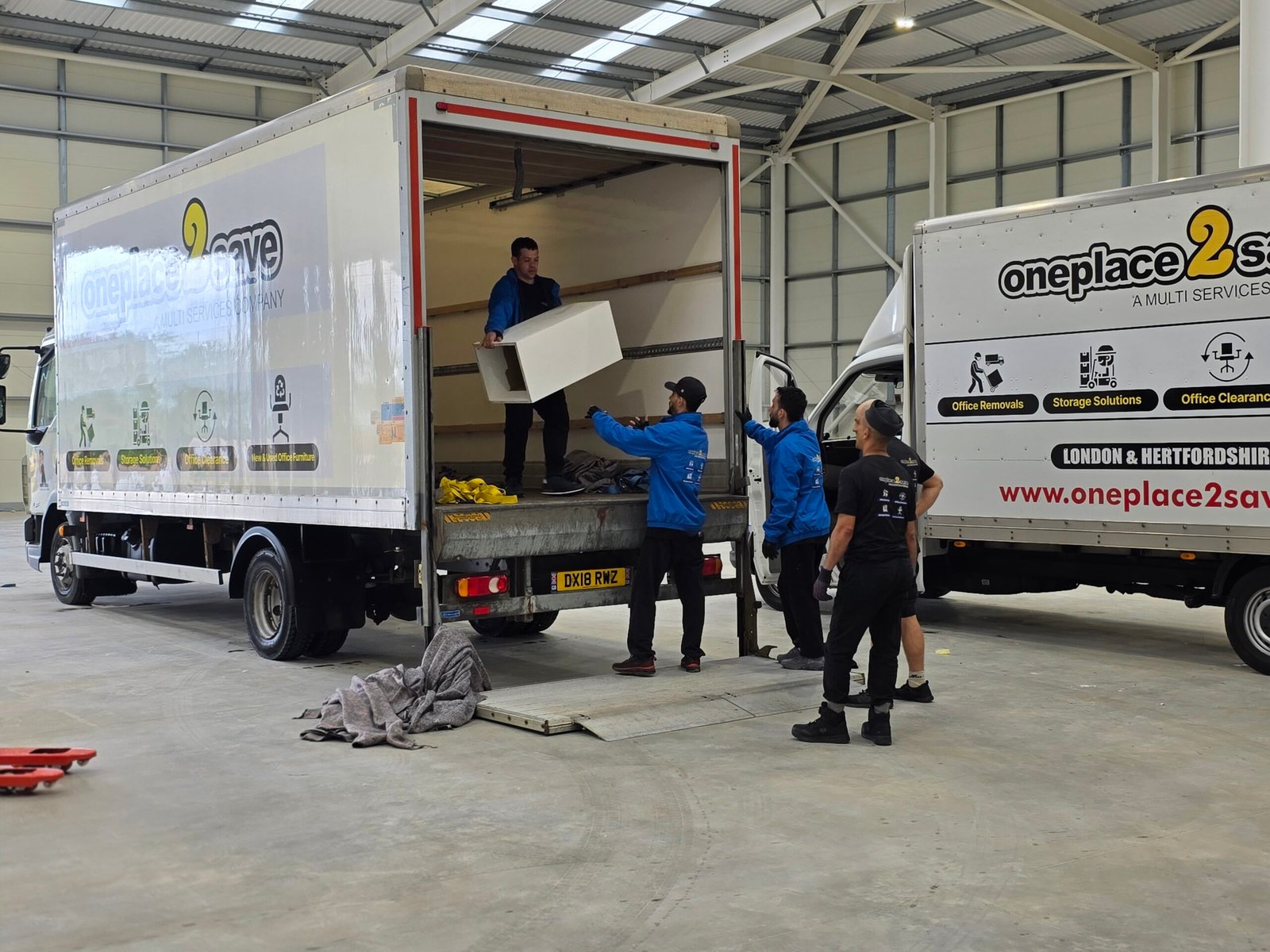 Oneplace2save crew loading furniture into a branded removal lorry.