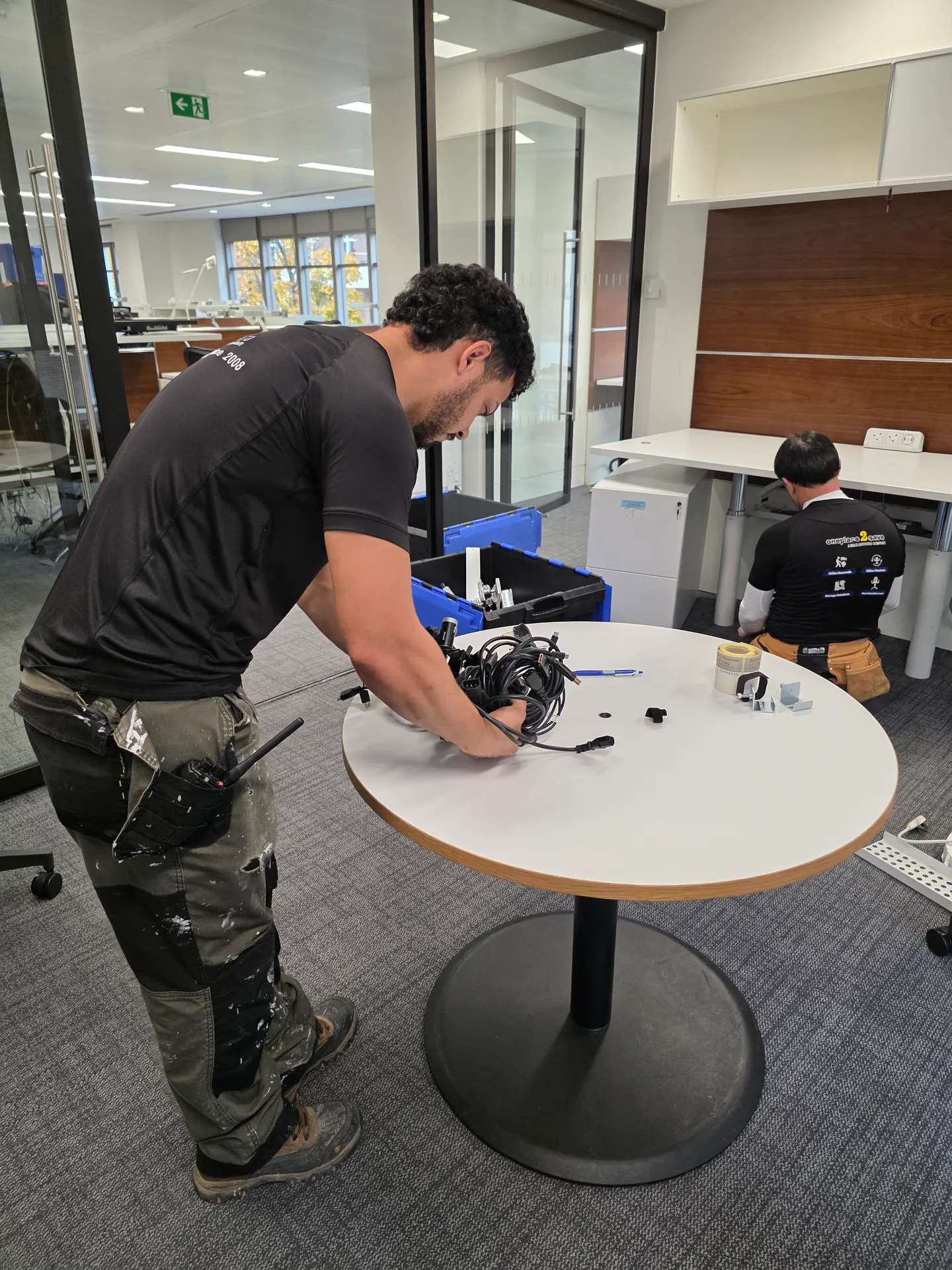 Oneplace2save team organising workstation components during office installation.