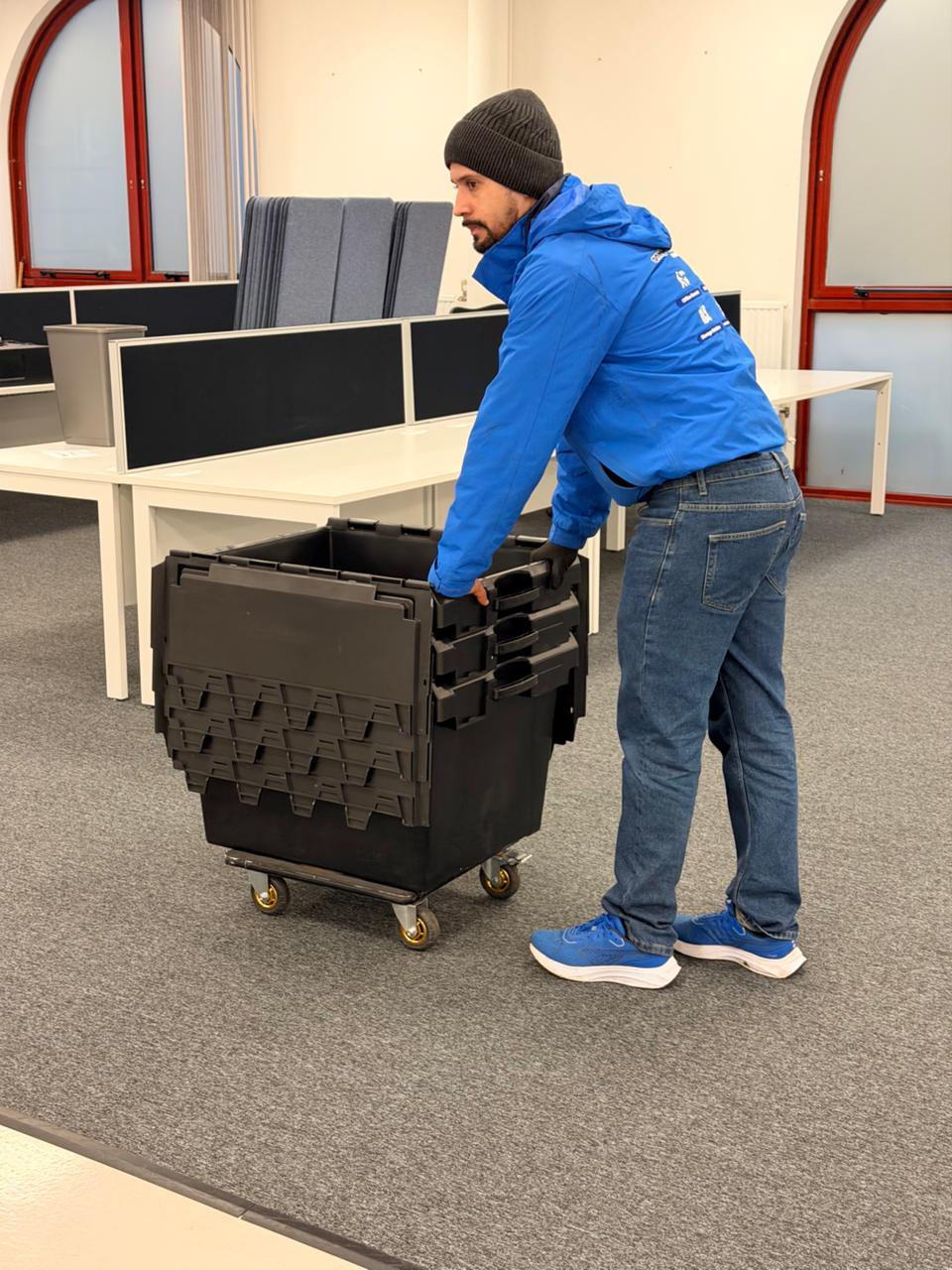 Oneplace2save team member moving office crates between installed workstations during the McLaren relocation.