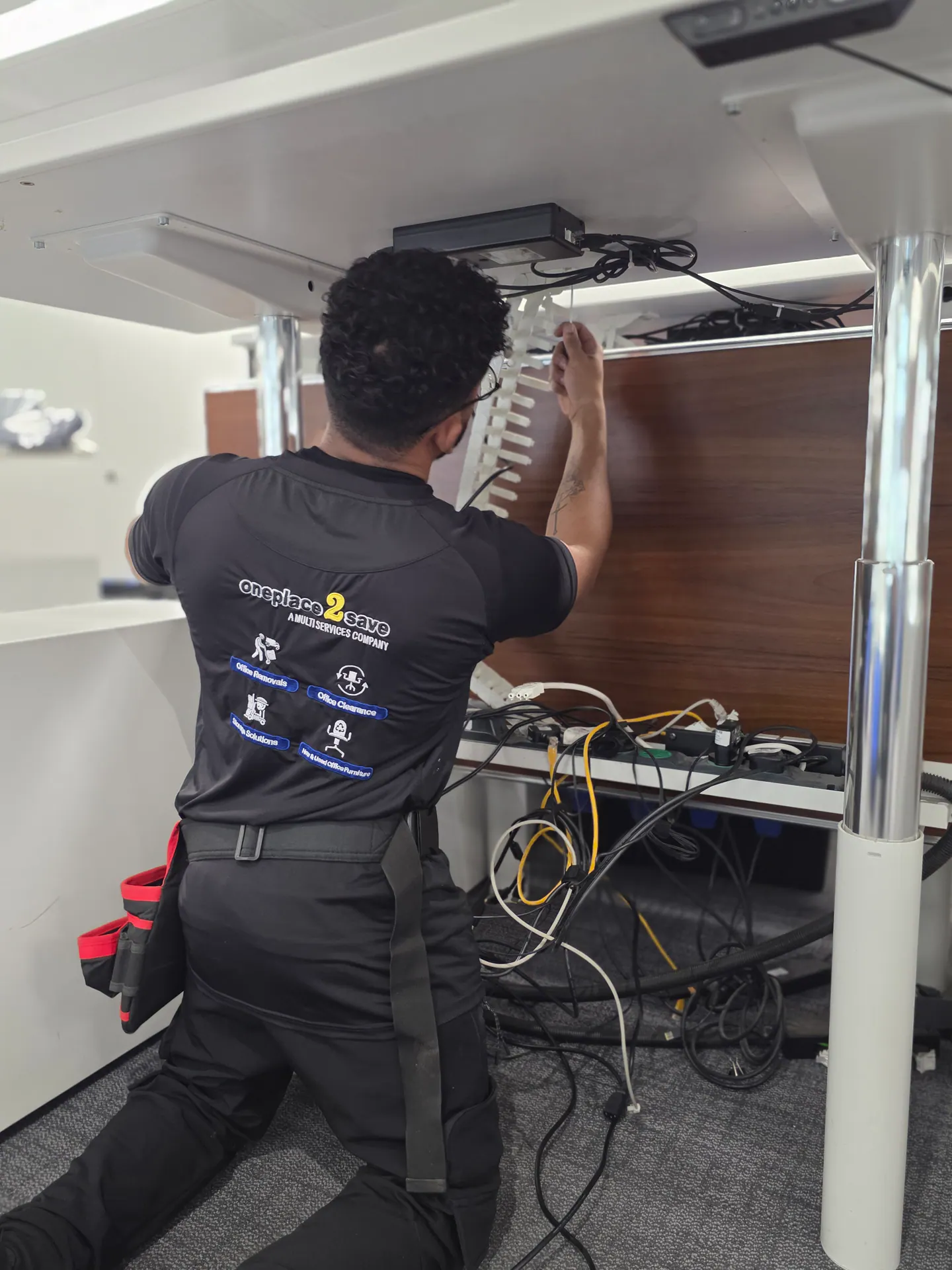 Oneplace2save technician organising cables beneath an Evercore workstation.
